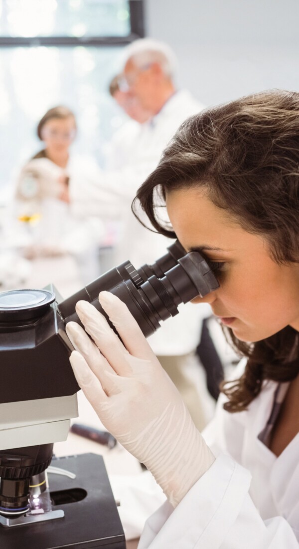 Eine junge Wissenschaftlerin am Mikroskop.