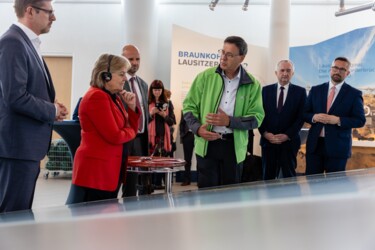 Mann mit grüner Jacke mit Gästen im Informationszentrum des Kraftwerks Boxberg