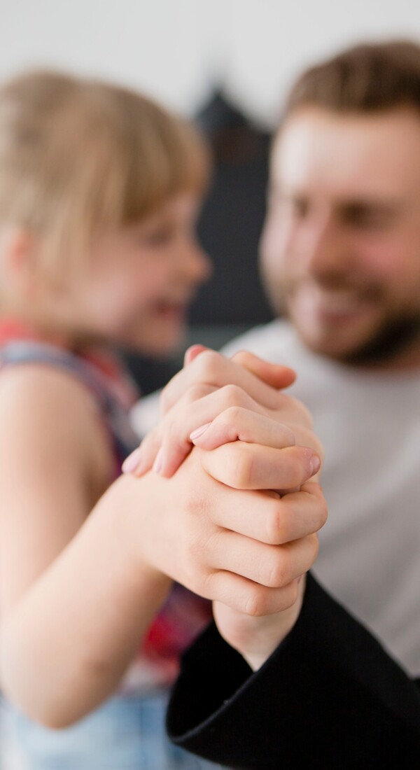 Mann mit Kind lachen und halten sich an den Händen