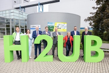 EU-Kommissarin Ferreira steht mit anderen Personen hinter großen grünen Zahlen und Buchstanden, die den Projektnamen "H2UB" ergeben