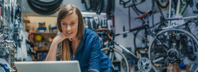 Frau am Laptop in einer Fahrrad-Werkstatt